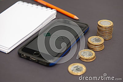 Florianopolis, Brazil. 28/09/2020: Top view of Pix logo on smartphone screen next to growing piles of coins. Pix is â€‹â€‹a new Editorial Stock Photo
